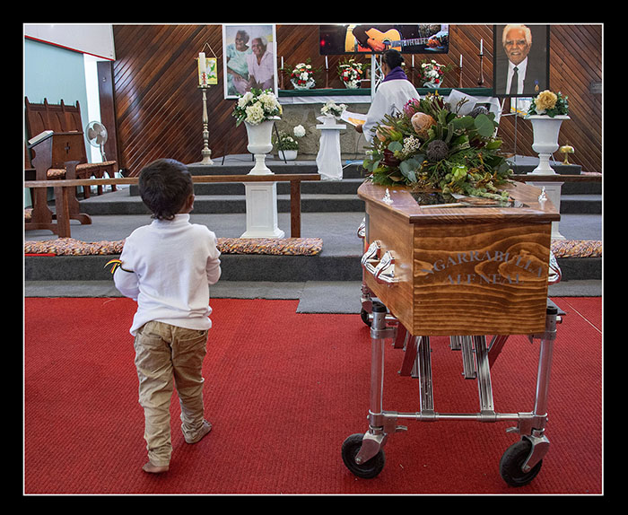 Funeral at Yarrabah of 100 year Elder Alf Neal OAM - 20th June 2023 Alf's great grandson Gary Neal stands by his great grandfathers coffin in St Alban';s Church Yarrabah - © image by Brian Cassey